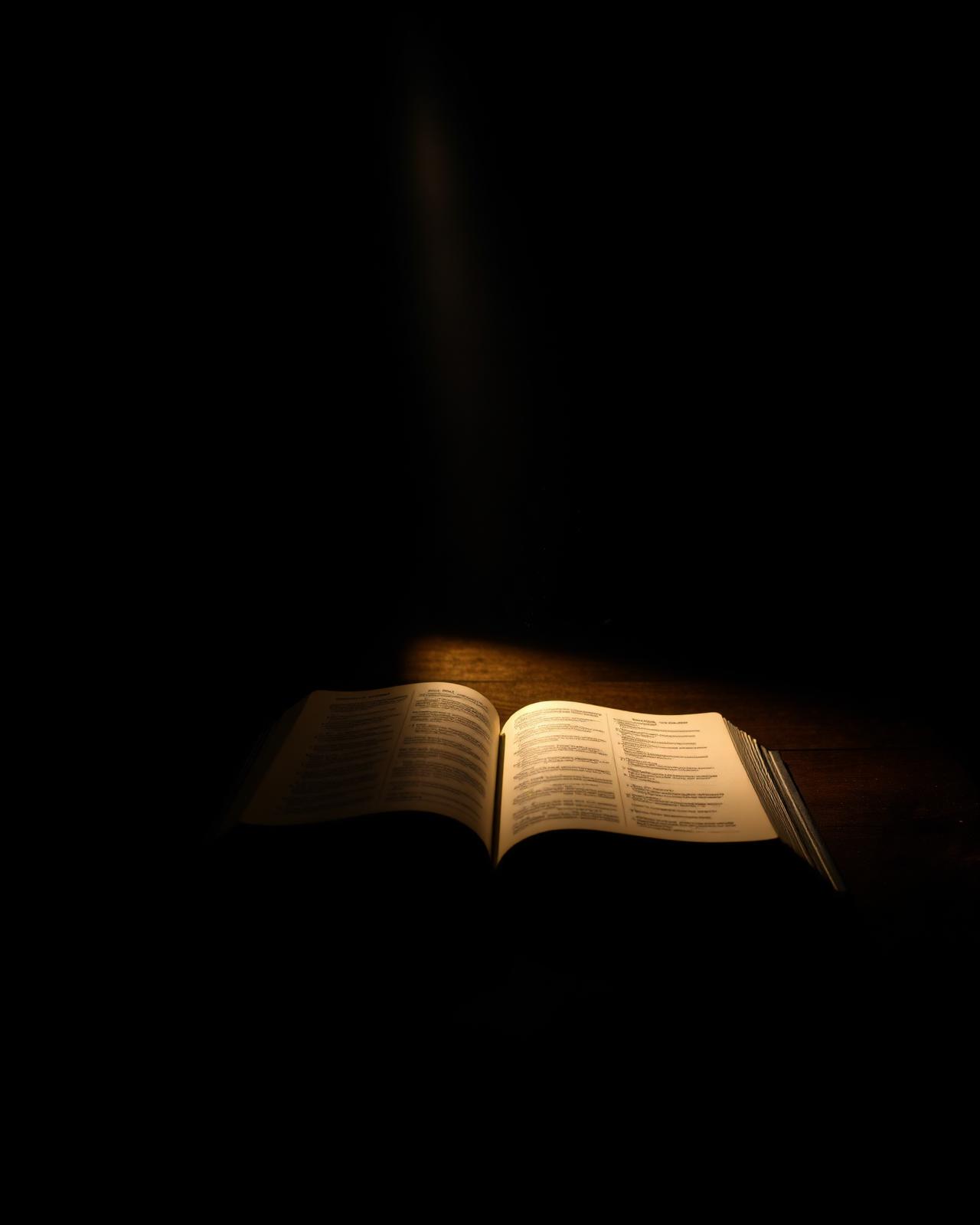 Livro aberto iluminado por luz dourada em ambiente escuro